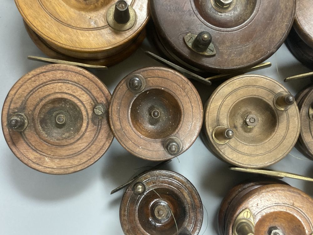 A collection of mahogany and brass fishing reels, largest 17.5cm (14)